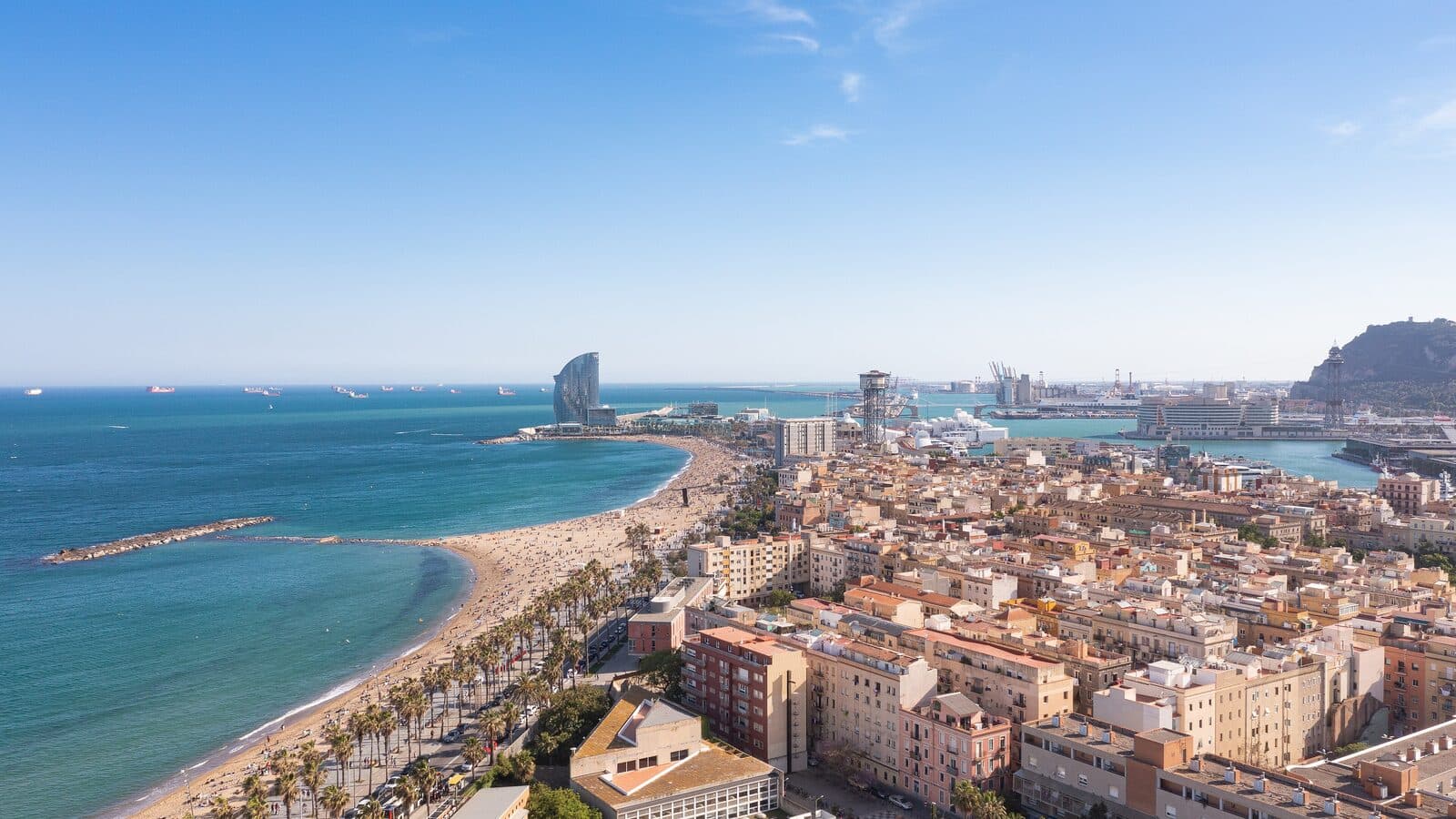 Aerial view of Barceloneta beach and the dense city blocks of Barcelona behind it.