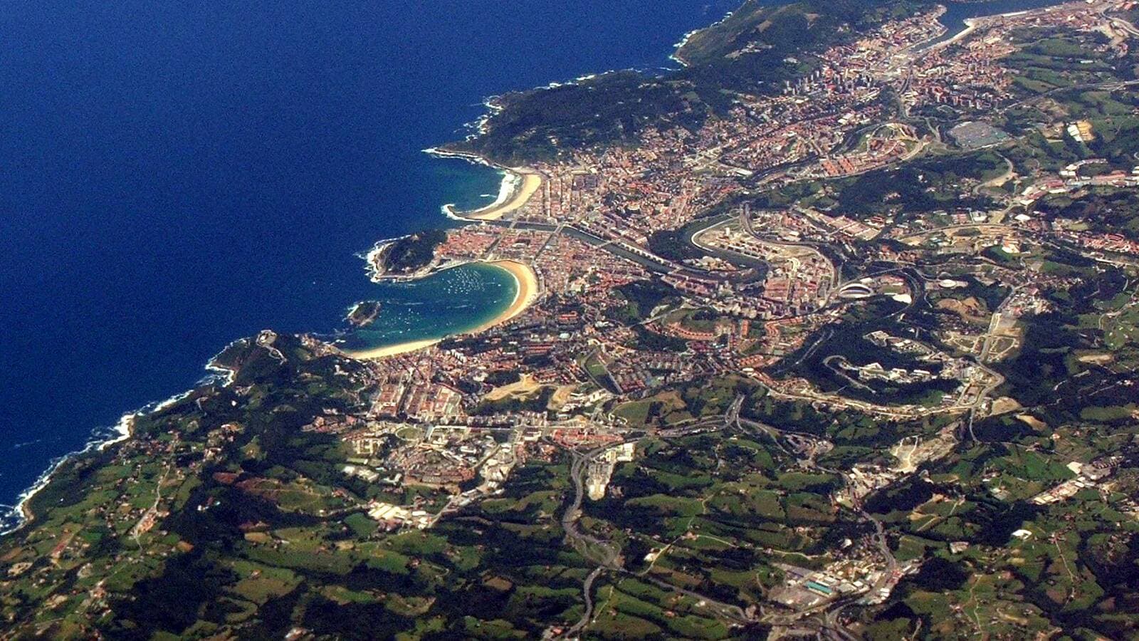 Aerial view of San Sebastián: the bay, the beach curving around it and the city streets behind.