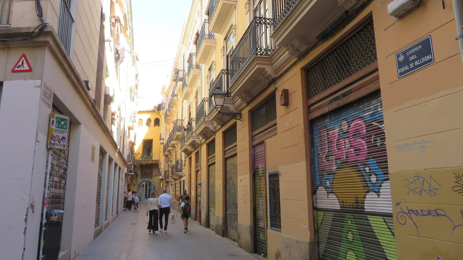 A narrow street in Valencia's Barrio del Carmen, with balconies and shuttered shopfronts.